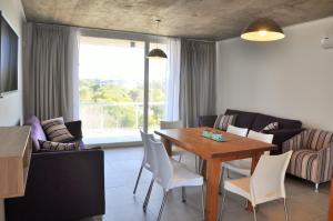 Una sala de estar con una mesa y sillas de madera. en CÁFILA Apart & Spa, en Las Gaviotas