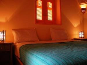 1 Schlafzimmer mit einem Bett mit blauer Bettwäsche und 2 Fenstern in der Unterkunft villa al diwan luxor in Luxor
