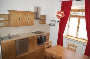 uma cozinha com armários de madeira, uma mesa e uma janela em Kronburger em Oberammergau