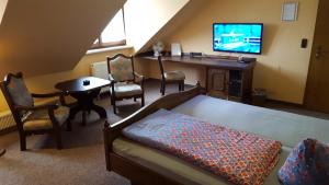 ein Wohnzimmer mit einem Bett, einem Tisch und einem TV in der Unterkunft Hotel Glindenberger Hof in Glindenberg