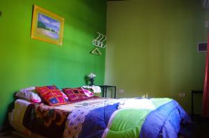 um quarto verde com uma cama com almofadas coloridas em Costa Aguacates em Posadas