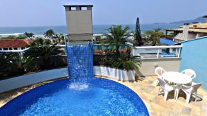 a swimming pool on a balcony with a table and chairs at Paramar Praia Grande in Ubatuba