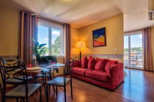 sala de estar con sofá rojo y mesa en Zenitude Hôtel-Résidences Les Jardins de Lourdes, en Lourdes