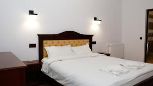 una camera da letto con un grande letto bianco con lenzuola bianche di Hanu lui Gica a Satu Mare