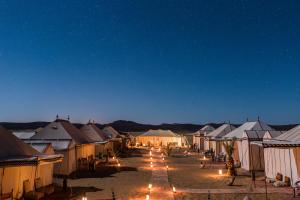 a group of tents in the desert at night at Desert Luxury Camp in Merzouga