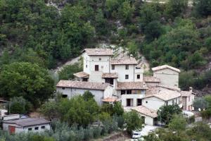 un gruppo di case su una collina con alberi di Valle del Belvedere a Spoleto