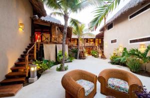 a patio with two chairs and a staircase with palm trees at Aamori Boutique Hotel (Only Adults) in San Agustinillo