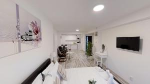 Habitación blanca con cama y TV de pantalla plana. en Sun Villa Residence en Bucarest