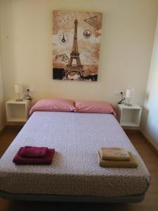 Zamora Apartments في سمورة: غرفة نوم بسرير وفوط وبرج ايفل