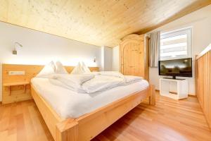 Schlafzimmer mit einem Bett mit weißer Bettwäsche und einem TV in der Unterkunft Hotel Lün in Brand