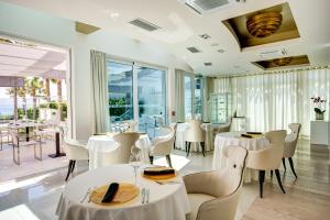 um restaurante com mesas e cadeiras brancas e janelas em Damianii Luxury Boutique Hotel & Spa em Omiš