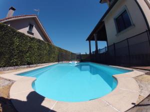 una grande piscina blu accanto a una casa di HHC - Holidays House Compostela a Santiago de Compostela