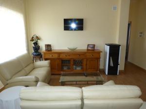 sala de estar con 2 sofás blancos y TV en Apartamento Zapatero en Trabanca