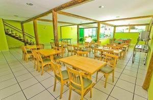 a restaurant with wooden tables and chairs and green walls at Pousada Luz do Sol in Rio das Ostras