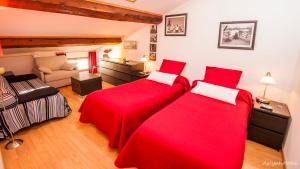 a bedroom with two red beds and a couch at ma chambre d'hôtes à Rivesaltes in Rivesaltes