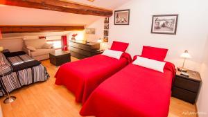 1 dormitorio con 2 camas rojas y sofá en ma chambre d'hôtes à Rivesaltes, en Rivesaltes