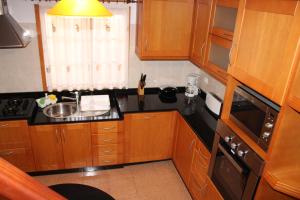 a small kitchen with wooden cabinets and a sink at Orchid House Madeira in Calheta