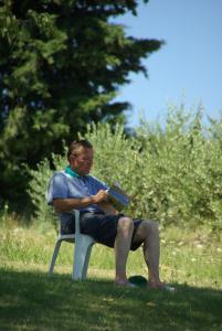 a man sitting on a bench reading a book at Angela Garden in Servigliano