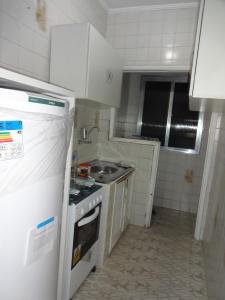 a small kitchen with a stove and a refrigerator at Apartamento São Vicente in São Vicente