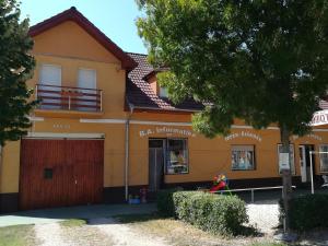 een geel huis met een garage en een boom bij Szahara Vendégház in Kerekegyháza