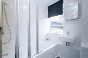 a white bathroom with a shower and a sink at Putney 1 Bed Apartment by BaseToGo in London +24 photos