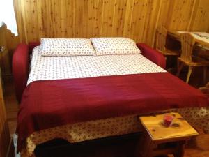 a bed with a red and white bedspread and a table at Mountain Charming Studio in Madesimo