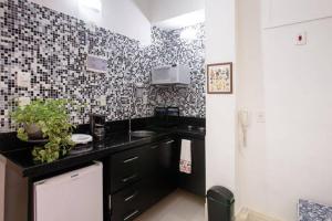 una cocina con armarios negros y una pared de azulejos blancos y negros. en Posto 5 Copacabana - quadra da praia 613, en Río de Janeiro