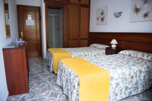 a hotel room with two beds and a table at Pension Los Geranios in Puerto de la Cruz