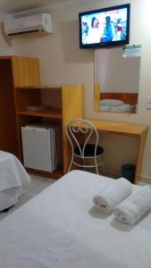 科拉蒂納是的住宿－Hotel Sao Miguel，卧室配有一张床,墙上配有电视。