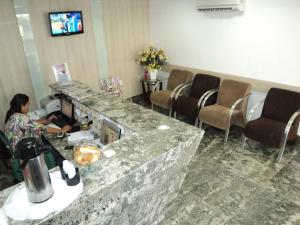 a woman sitting at a counter in a waiting room at Hotel Sao Miguel in Colatina