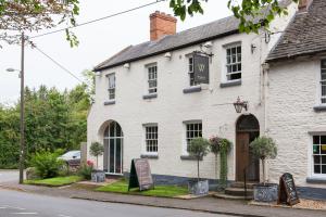 a white building with a sign in front of it at The Wychwood Inn in Shipton under Wychwood