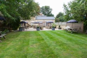 a lawn with picnic tables and umbrellas in a yard at The Wychwood Inn in Shipton under Wychwood +47 photos