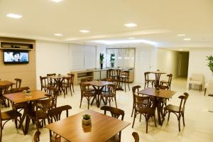 um restaurante com mesas e cadeiras de madeira e uma cozinha em Hotel Vizzion em Paraí