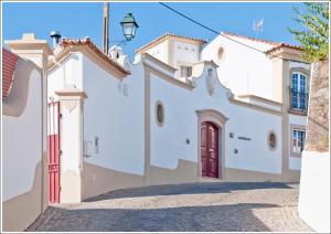 a white house with a red door on a street at Casa d´Alegrete in Alegrete
