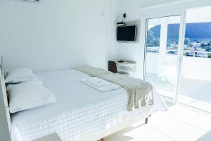 a white bedroom with a bed and a large window at Hotel Vizzion in Paraí