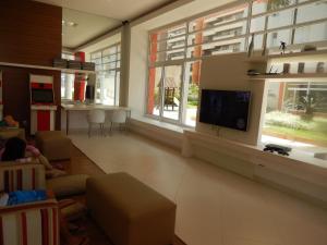 a living room with a tv and a large window at Vista ao Mar & Lazer Total in Guarujá
