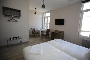 um quarto com 2 camas e uma mesa com cadeiras em L'Hotel De France em Roubaix