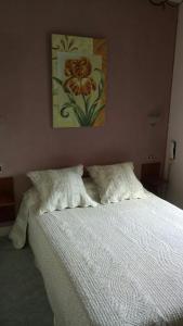 a white bed with two pillows and a painting on the wall at Auberge La Croix Blanche in Combreux