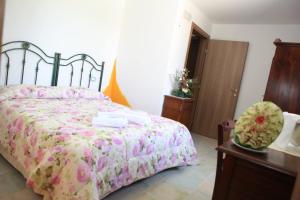 a bedroom with a bed with a floral bedspread at Agriturismo Il Pavone in Torre Lapillo