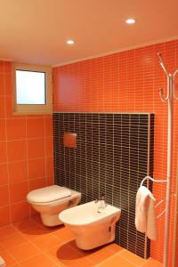 y baño con azulejos de color naranja, aseo y lavamanos. en B&B Solacium, en Matera