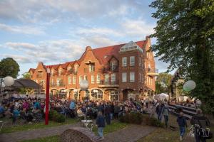 Eine Menschenmenge, die vor einem Gebäude steht in der Unterkunft Arkadenhaus - Hotel Freiherr von Schwarzenberg in Papenburg