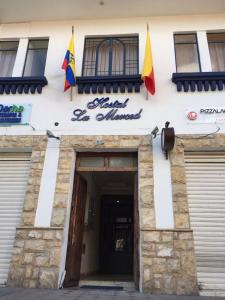een gebouw met twee vlaggen vooraan bij Hostal la Merced in Cuenca