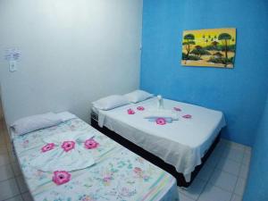 Dos camas en una habitación con flores rosas. en Pousada Costa dos Corais, en Maragogi