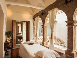 a bedroom with a bed and a large window at Inkaterra La Casona Relais & Chateaux in Cusco