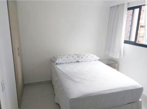 a white bed in a white room with a window at Flat em Boa Viagem in Recife +19 photos