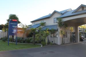 a hotel with a sign in front of a building at Aquarius Motor Inn in Mount Maunganui