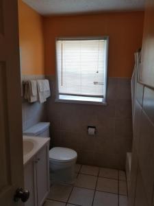 a bathroom with a toilet and a sink and a window at Sooner Motel in Stroud
