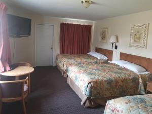 a hotel room with three beds and a table at Sooner Motel in Stroud