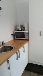 a kitchen with a sink and a microwave on a counter at Mauao Studio in Mount Maunganui