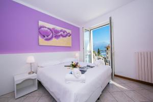 a bedroom with a white bed and a purple wall at Residence Riva del Lario in Gravedona